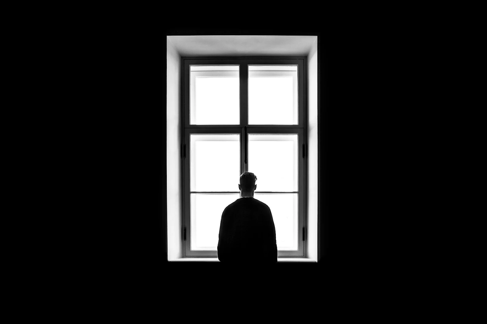 A silhouette of a person standing at a window