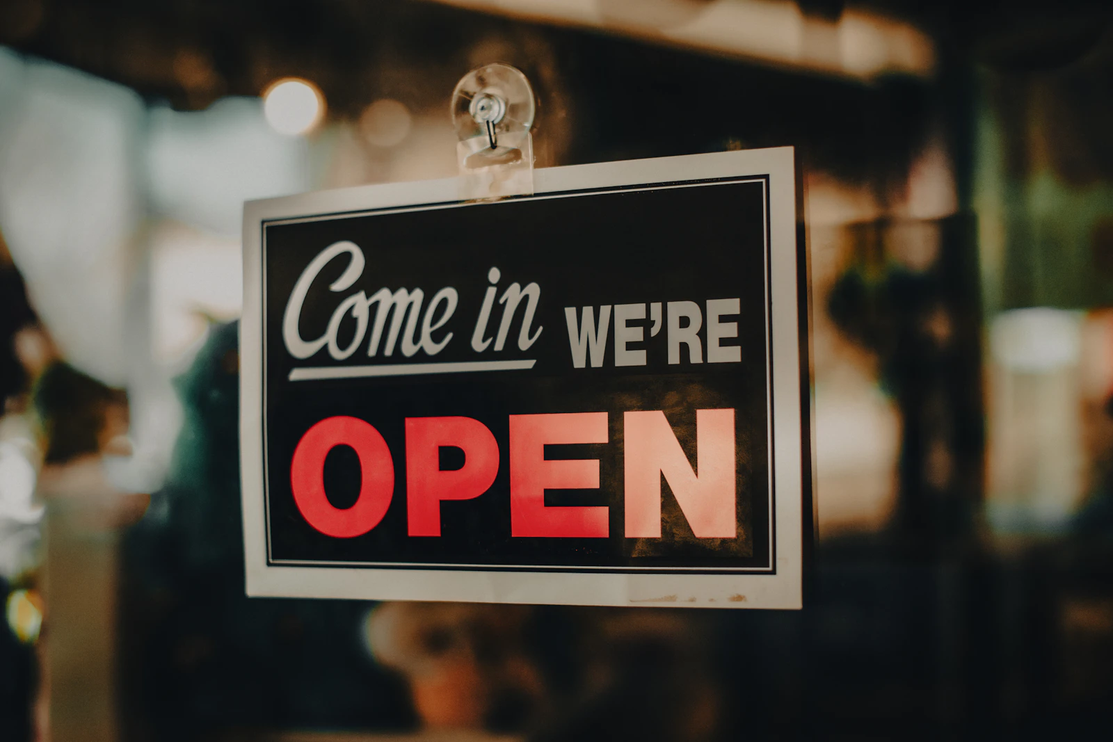 A sign in a shop window that says come in, we're open