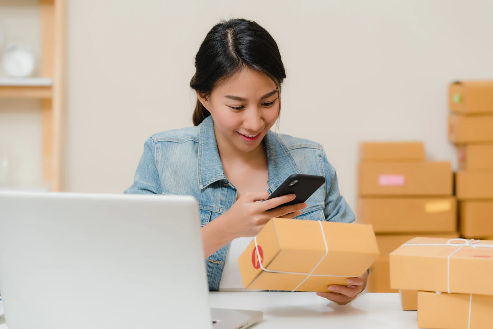 A small business owner smiling as she checks an order beside packed boxes