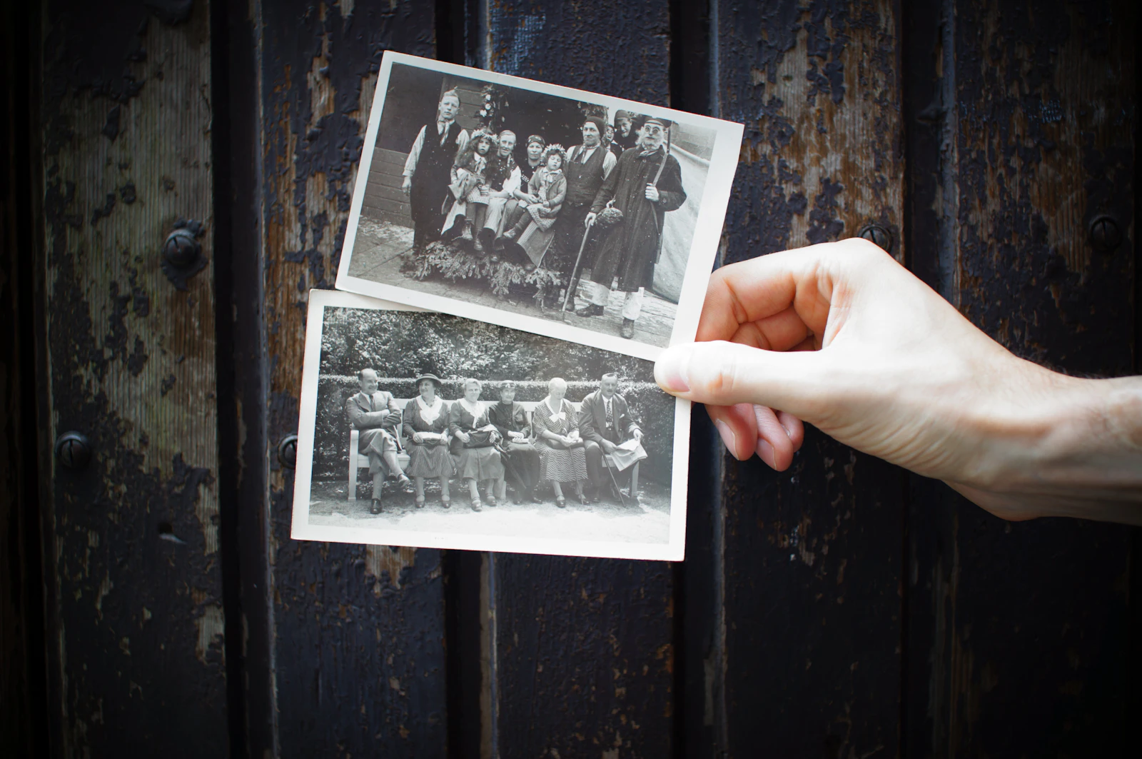 A hand holding old black-and-white photographs
